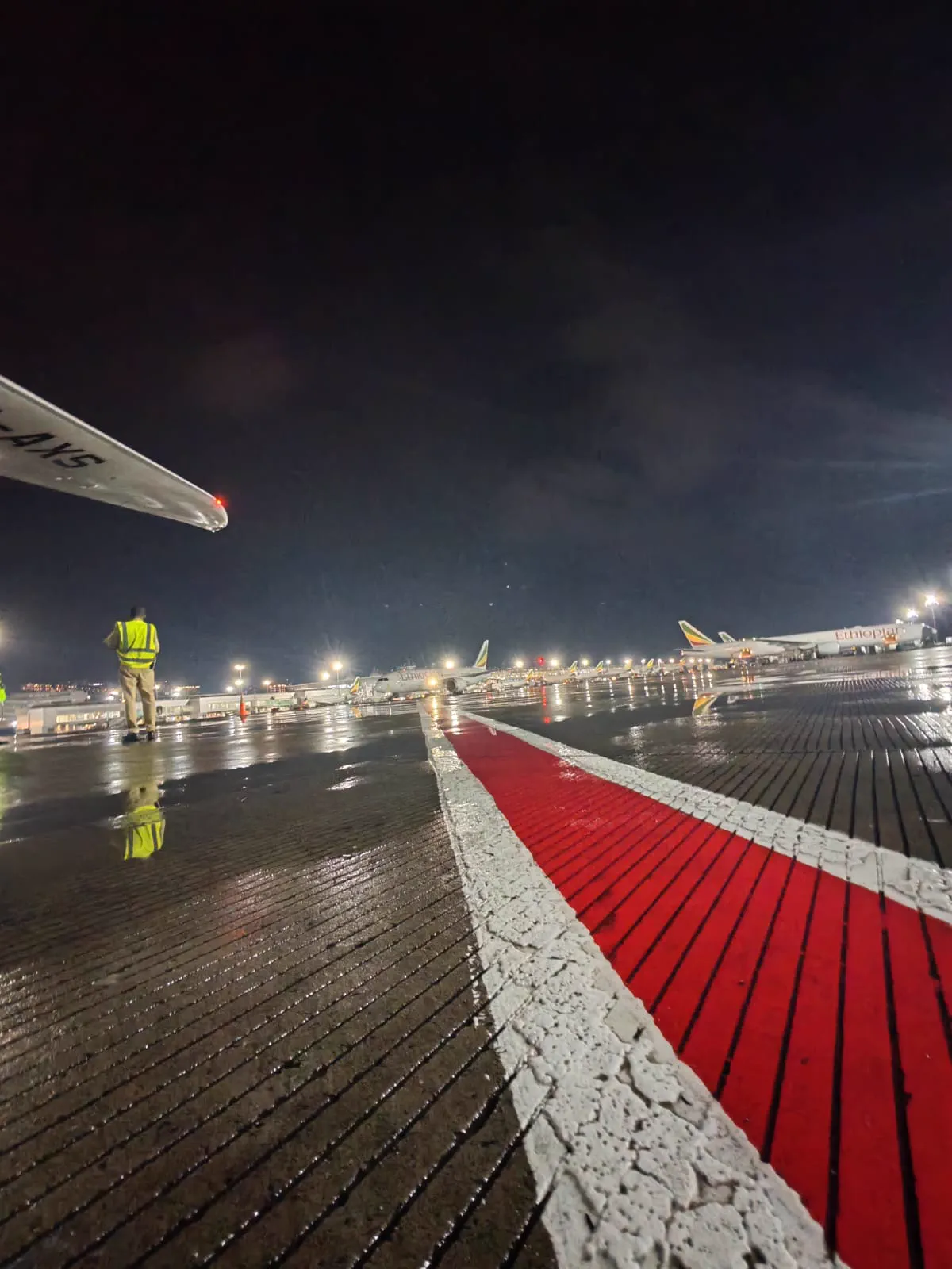Ethiopian Airlines aircraft on a rain-soaked Addis Ababa Bole airport apron at night