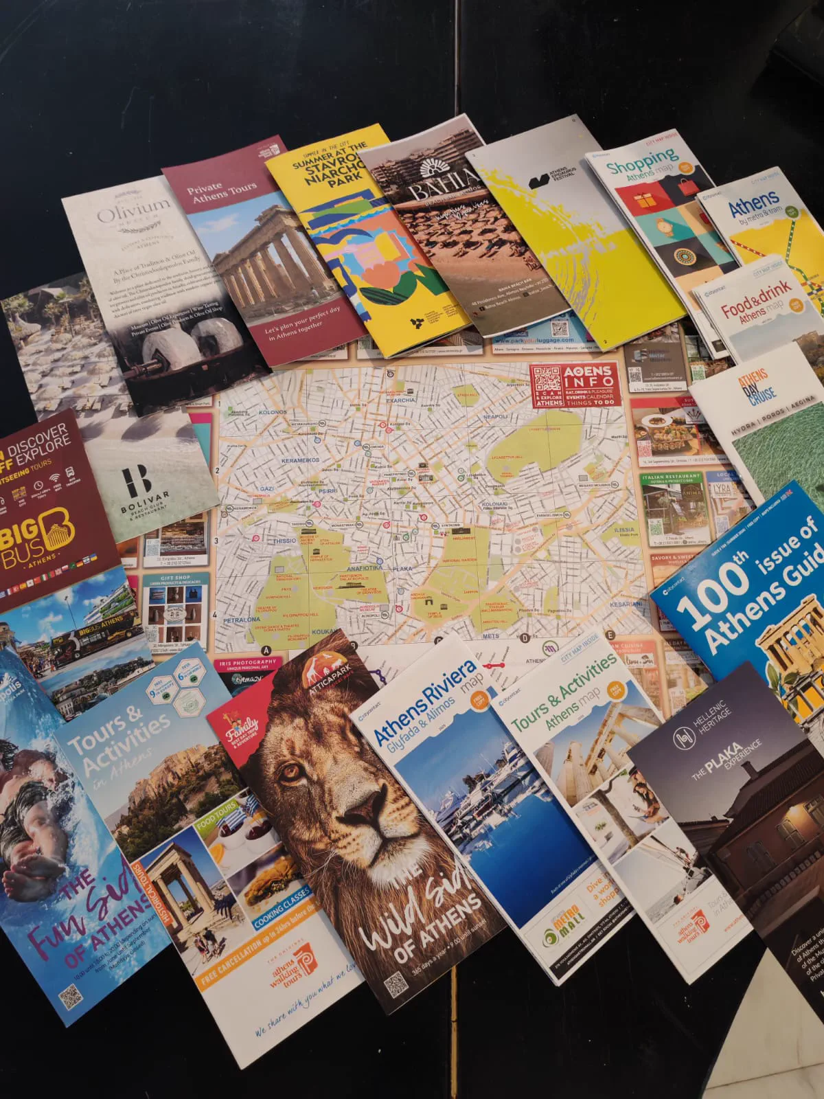A table covered in Athens tourist brochures, tour leaflets and a fold-out city map
