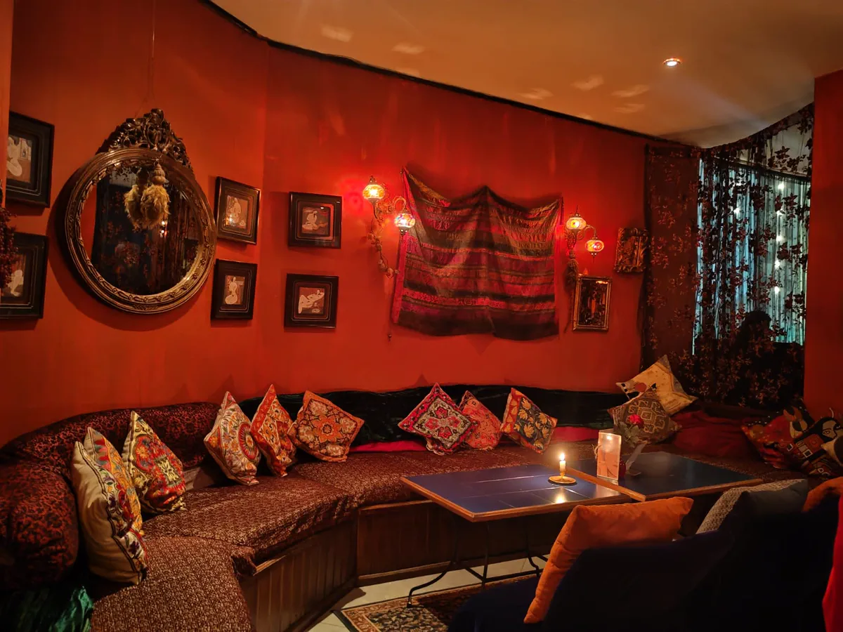 Candlelit Moroccan-style lounge inside The Black Rose in Addis Ababa, with patterned cushions and deep red walls