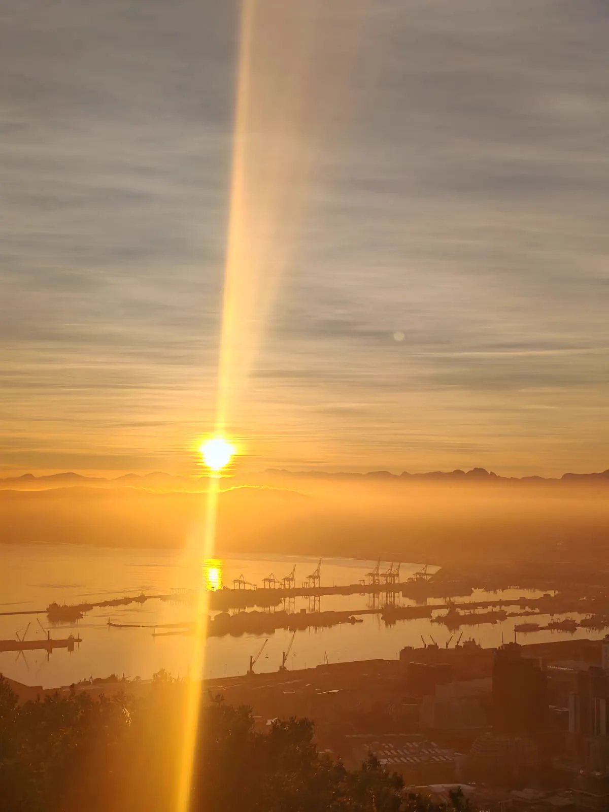 Sunrise breaking over Cape Town harbour and the distant mountains, seen from Lions Head