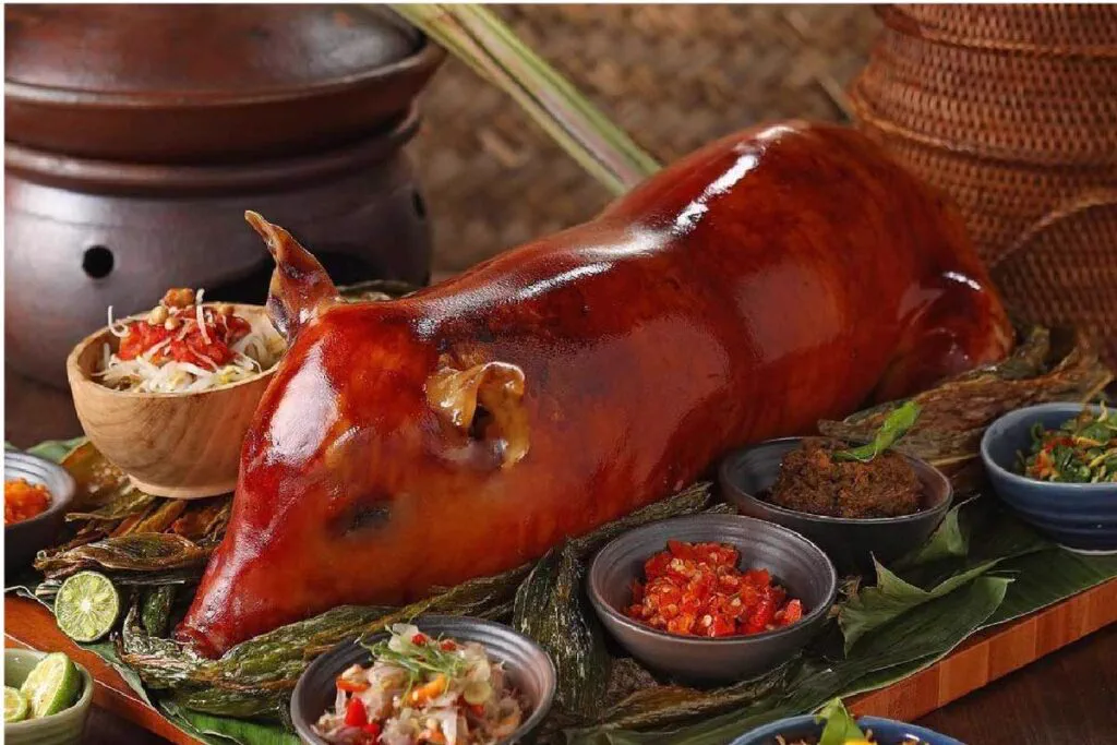 Balinese babi guling, spit-roasted suckling pig, served with sambal and side dishes