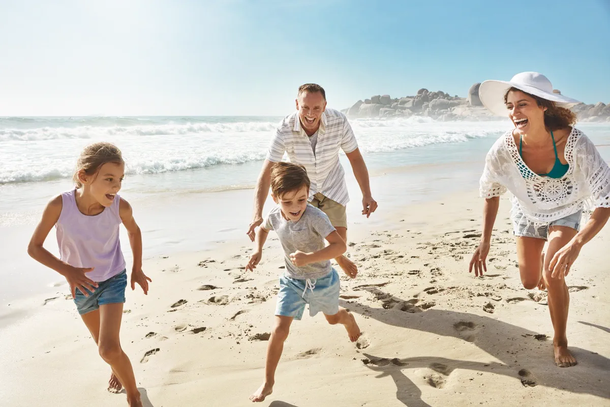 Family running and laughing together on a sunny beach