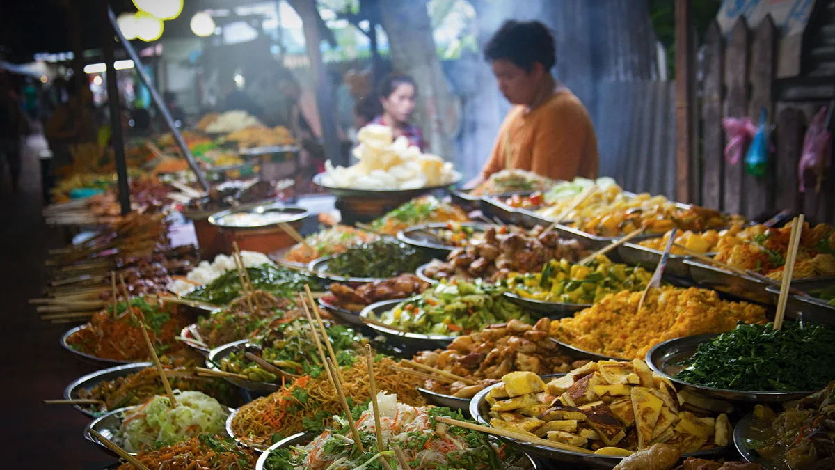 Trays of Thai street food at a busy night-market stall