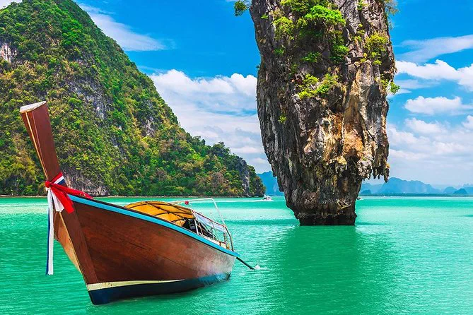 Longtail boat in turquoise water near Khao Tapu, the limestone pinnacle known as James Bond Island, in Phang Nga Bay