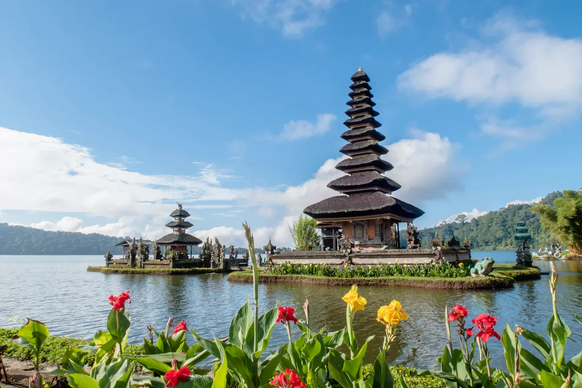 Pura Ulun Danu Beratan water temple on Lake Bratan in Bali, with tiered shrines and green hills under a blue sky