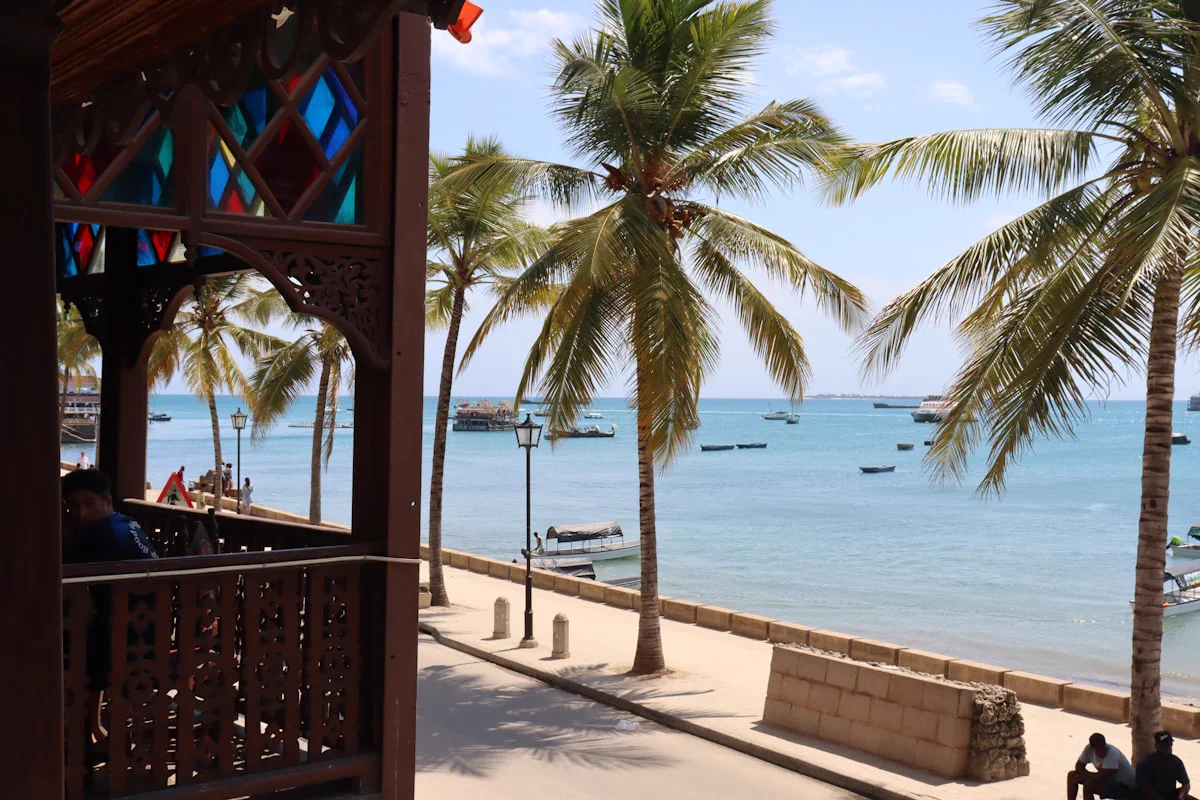 Palm-lined Stone Town seafront overlooking turquoise water and moored boats, Zanzibar